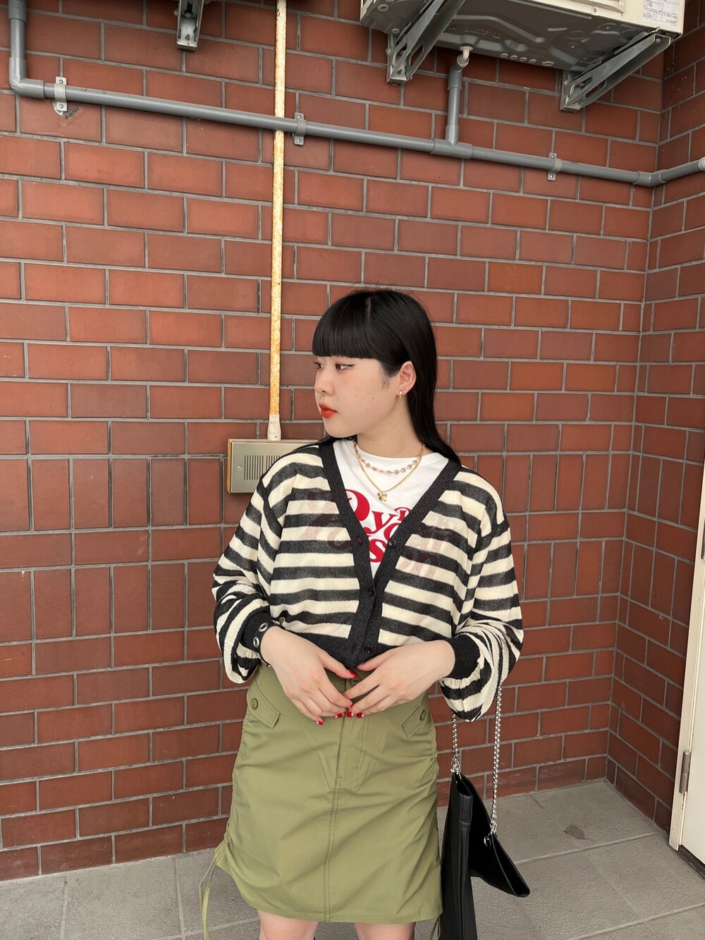 グリーン系のスカート、ブラック系のカーディガン/ボレロ、ホワイト系のTシャツ/カットソーを着用したレディースの夏コーディネートの6枚目の写真