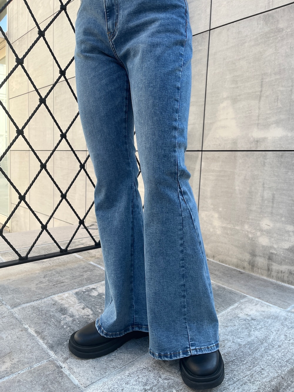 オレンジ系のワンピース、ブラック系のブーツ、ブルー系のデニムパンツを着用したレディースの冬コーディネートの8枚目の写真