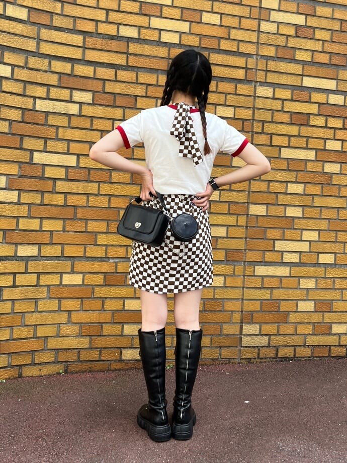 ブラック系のブーツ、ホワイト系のシャツ/ブラウス、ブラック系のハンドバッグを着用したレディースの夏コーディネートの2枚目の写真