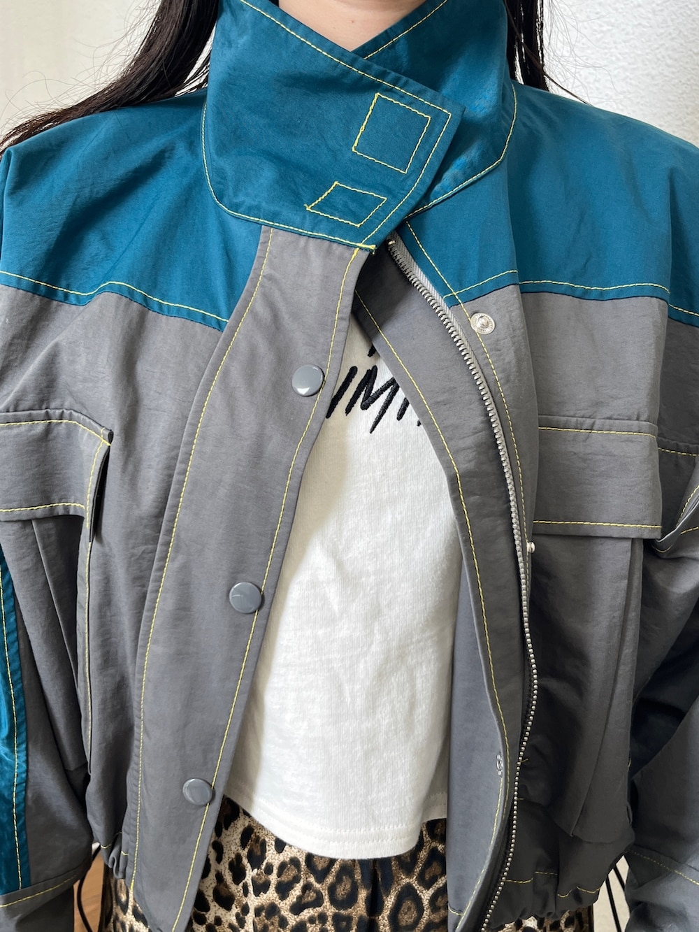 グリーン系のブルゾン、ブラウン系のその他パンツ、ホワイト系のタンクトップを着用したレディースの秋コーディネートの6枚目の写真