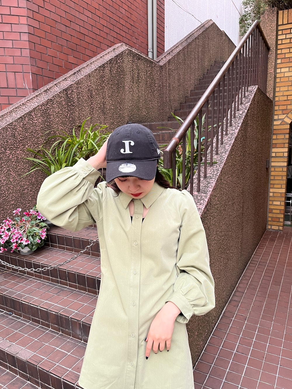 グリーン系のワンピース、ブラック系のブーツ、ブラック系のキャップを着用したレディースの冬コーディネートの6枚目の写真