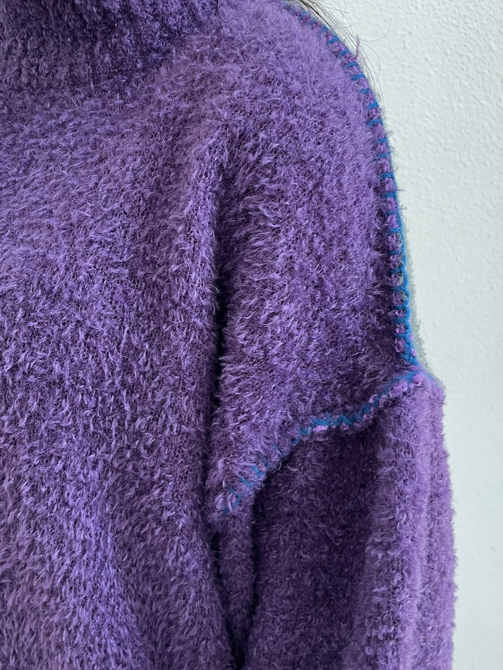 パープル系のニット/セーター、ブルー系のデニムパンツ、グリーン系のボストンバッグを着用したレディースの秋コーディネートの7枚目の写真