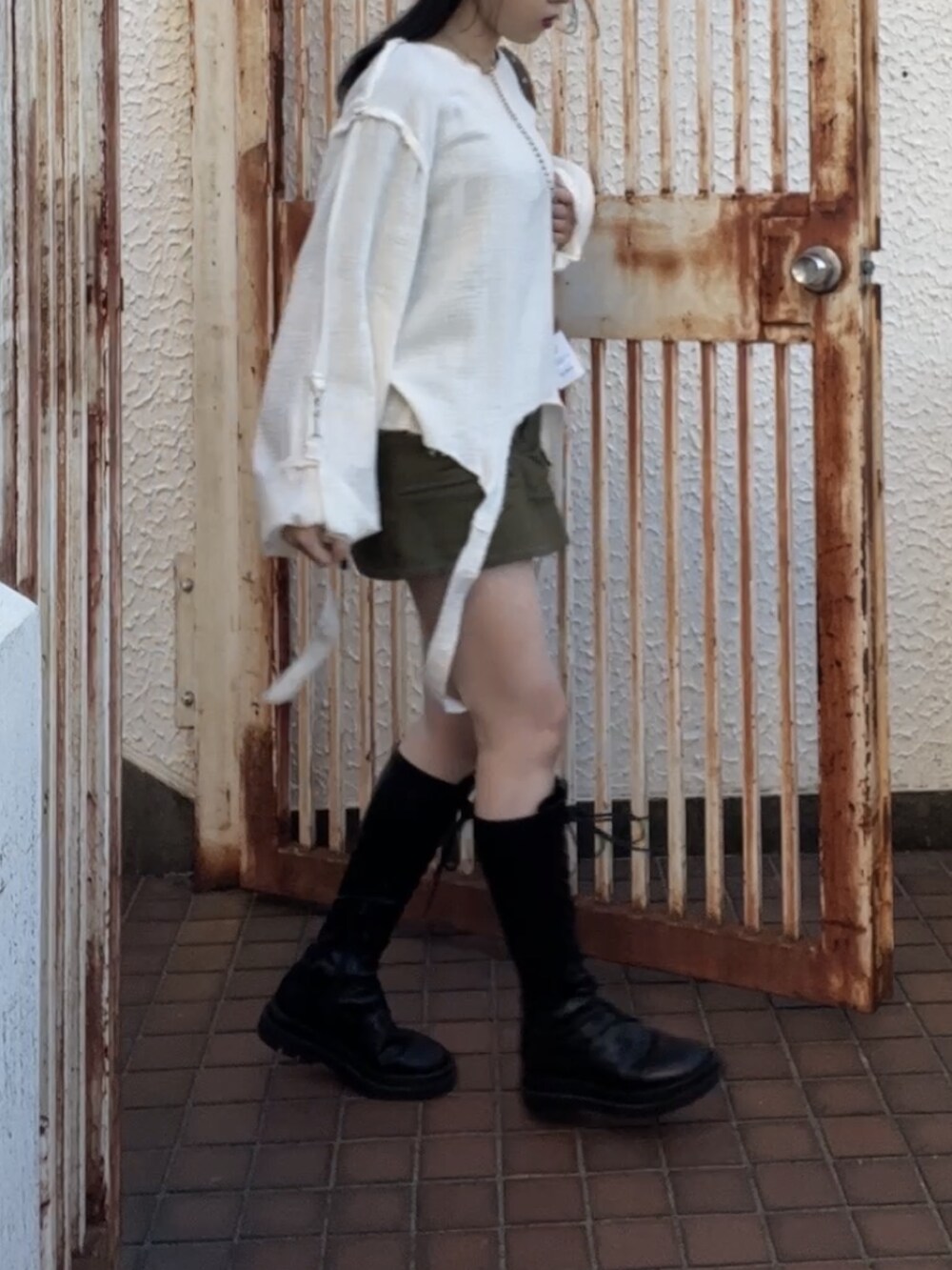 ブラック系のスカート、ブラック系のブーツ、レッド系のショルダーバッグを着用したレディースの冬コーディネートの3枚目の写真