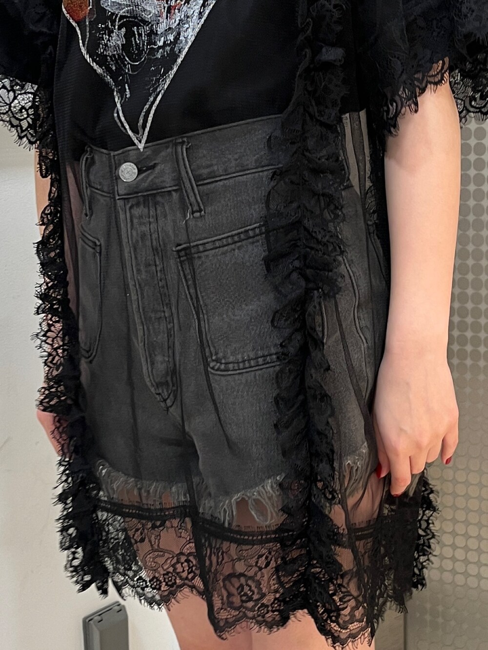 ブラック系のワンピース、ブラック系のブーツ、ブラック系のデニムパンツを着用したレディースの春コーディネートの7枚目の写真