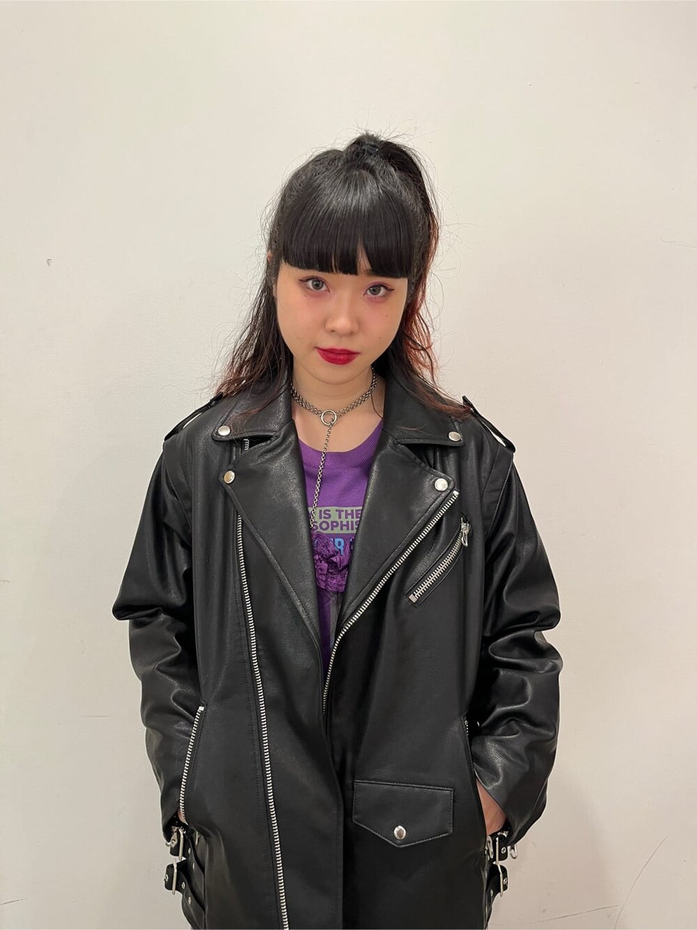 ブラック系のライダースジャケット、パープル系のワンピースを着用したレディースの秋コーディネートの4枚目の写真