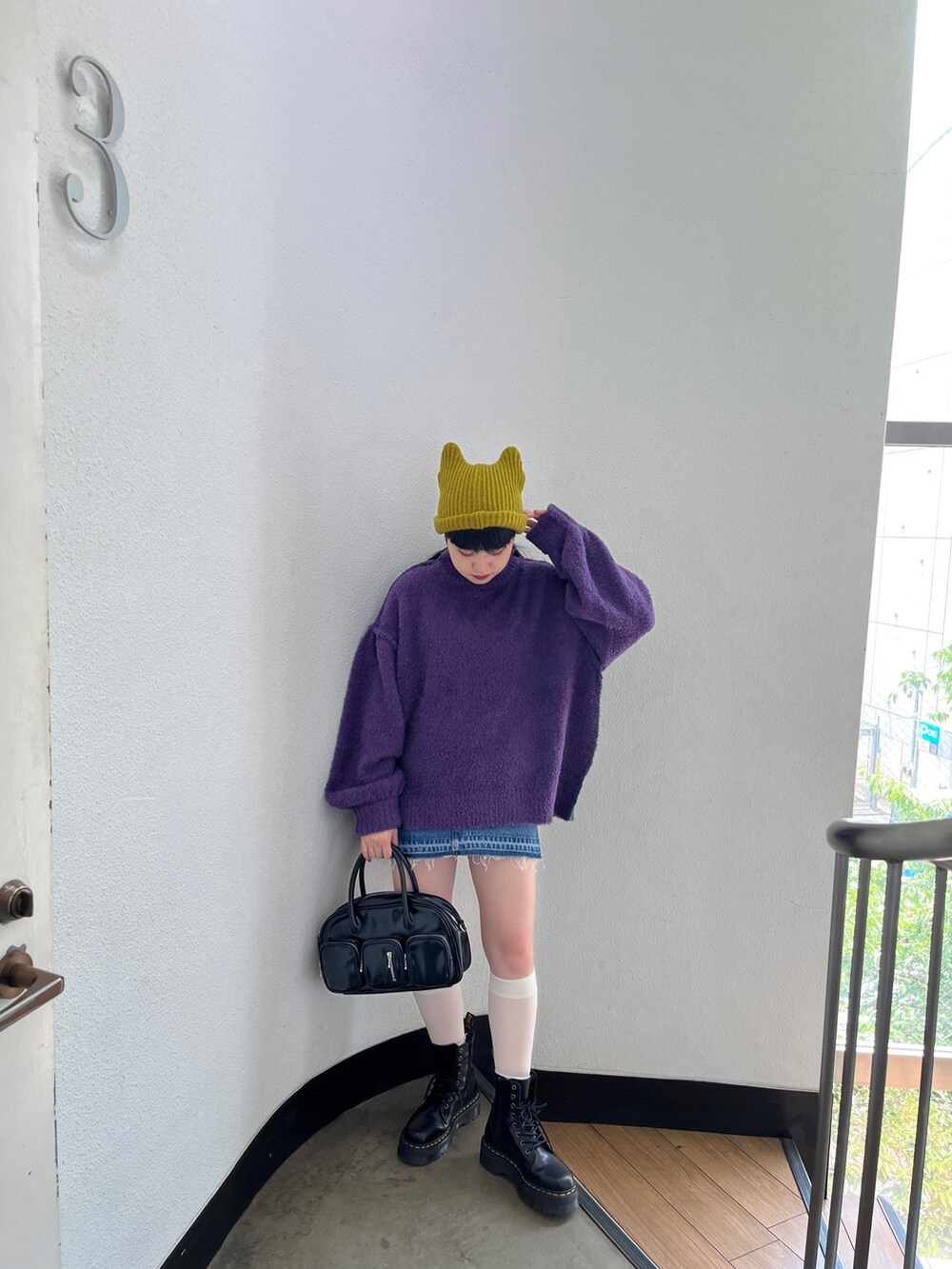 パープル系のニット/セーター、ブルー系のデニムパンツ、グリーン系のボストンバッグを着用したレディースの秋コーディネートの3枚目の写真