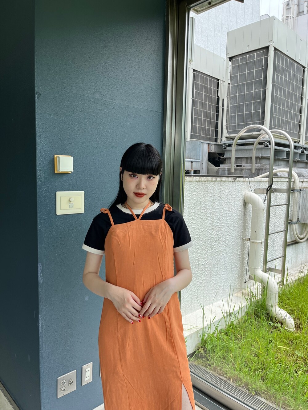 オレンジ系のワンピース、ホワイト系のTシャツ/カットソー、ブラック系のブーツを着用したレディースの夏コーディネートの5枚目の写真