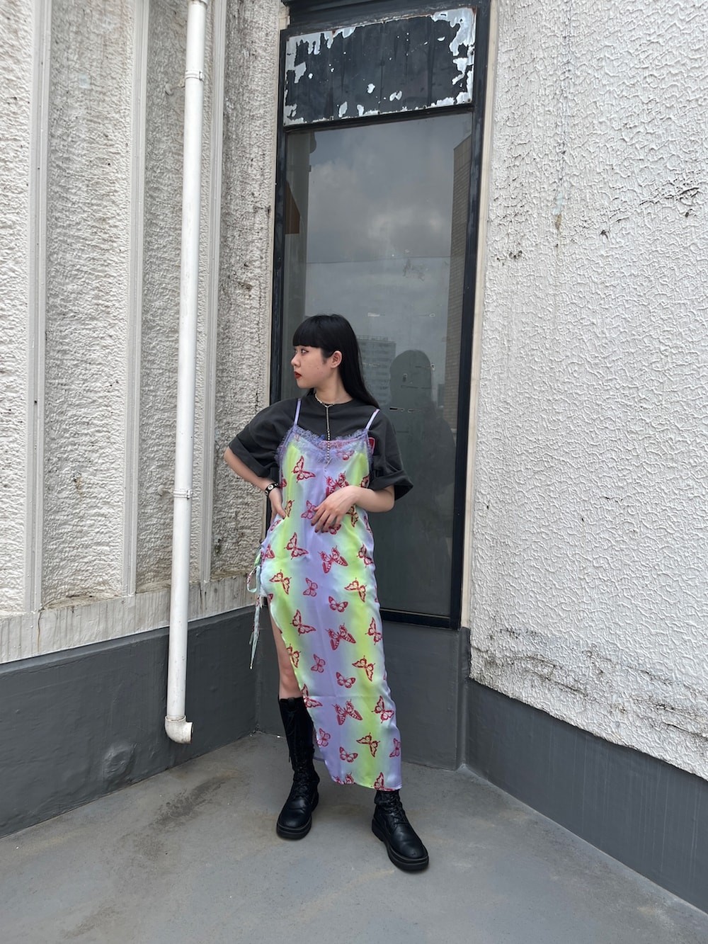 パープル系のワンピース、ブラック系のTシャツ/カットソー、ブラック系のブーツを着用したレディースの春コーディネートの2枚目の写真