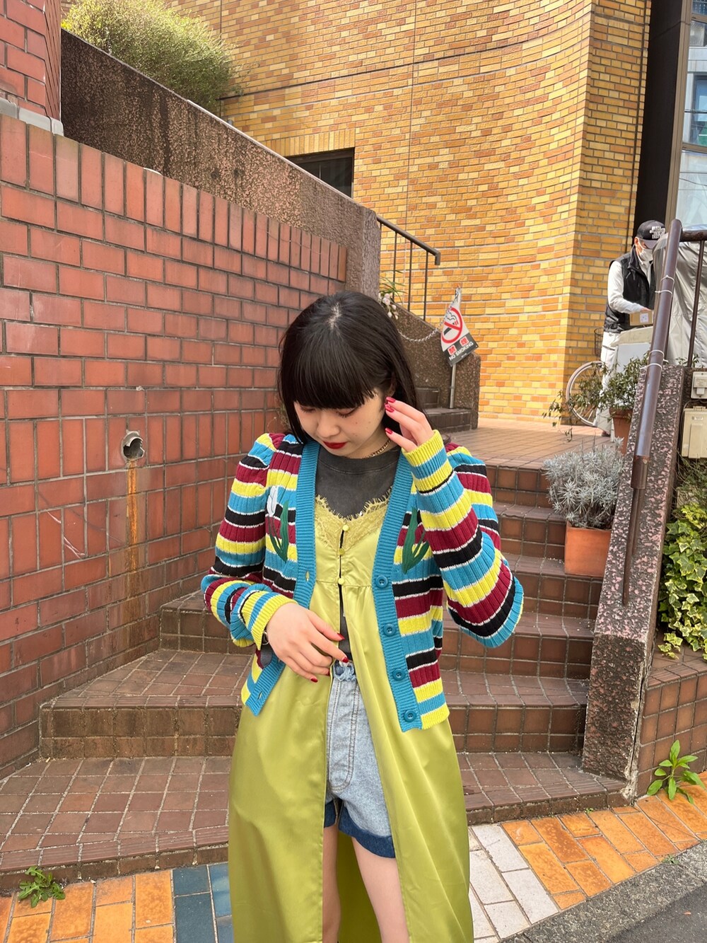 グリーン系のワンピース、ブラック系のブーツ、ブルー系のデニムパンツを着用したレディースの春コーディネートの6枚目の写真