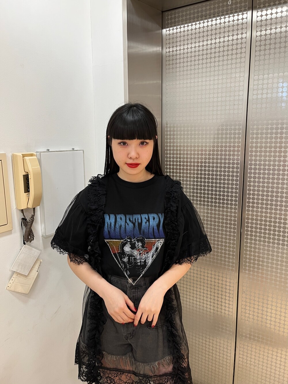 ブラック系のワンピース、ブラック系のブーツ、ブラック系のデニムパンツを着用したレディースの春コーディネートの4枚目の写真