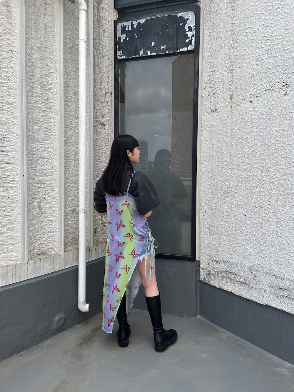 パープル系のワンピース、ブラック系のTシャツ/カットソー、ブラック系のブーツを着用したレディースの春コーディネートの3枚目の写真