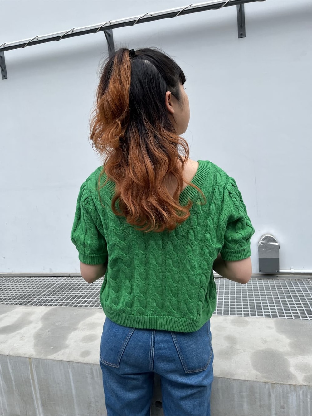 グリーン系のキャミソール、グリーン系のニット/セーター、ブラック系のサングラスを着用したレディースの春コーディネートの5枚目の写真