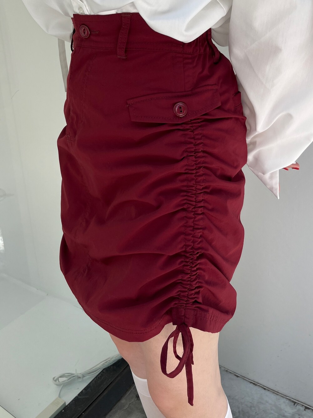 レッド系のスカート、ホワイト系のシャツ/ブラウス、ブラック系のキャップを着用したレディースの夏コーディネートの7枚目の写真