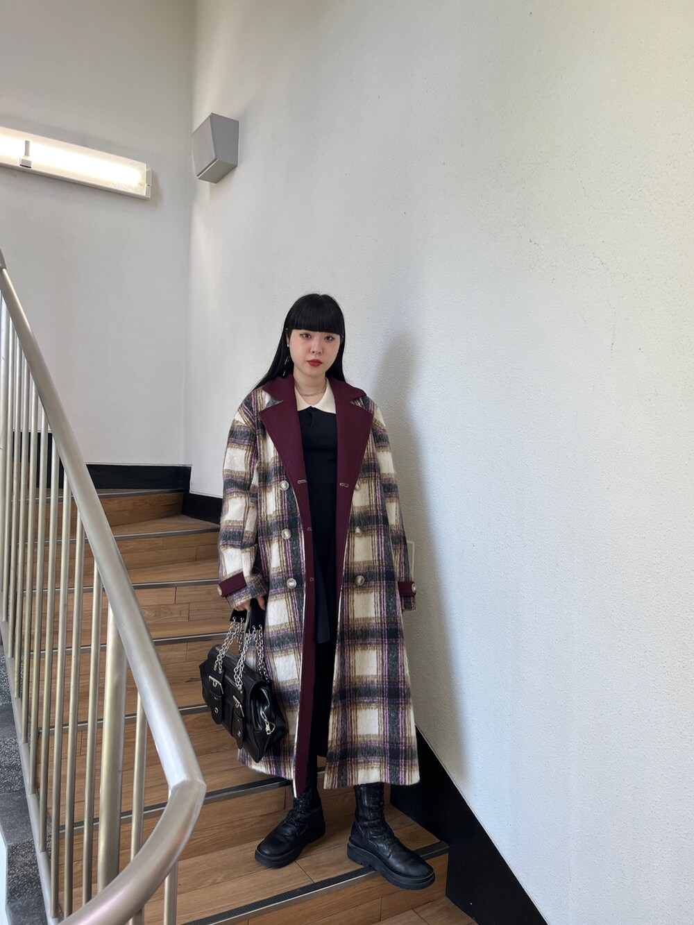 ブラック系のブーツ、ブラック系のハンドバッグ、ホワイト系のチェスターコートを着用したレディースの夏コーディネートの2枚目の写真