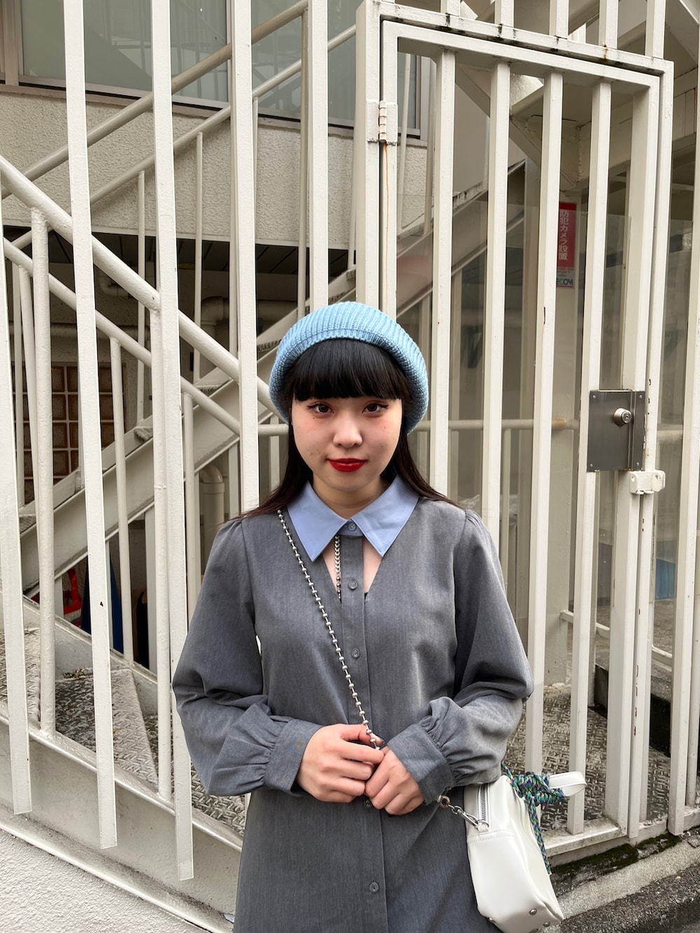 グレー系のワンピース、ブラック系のブーツ、ホワイト系のショルダーバッグを着用したレディースの冬コーディネートの6枚目の写真