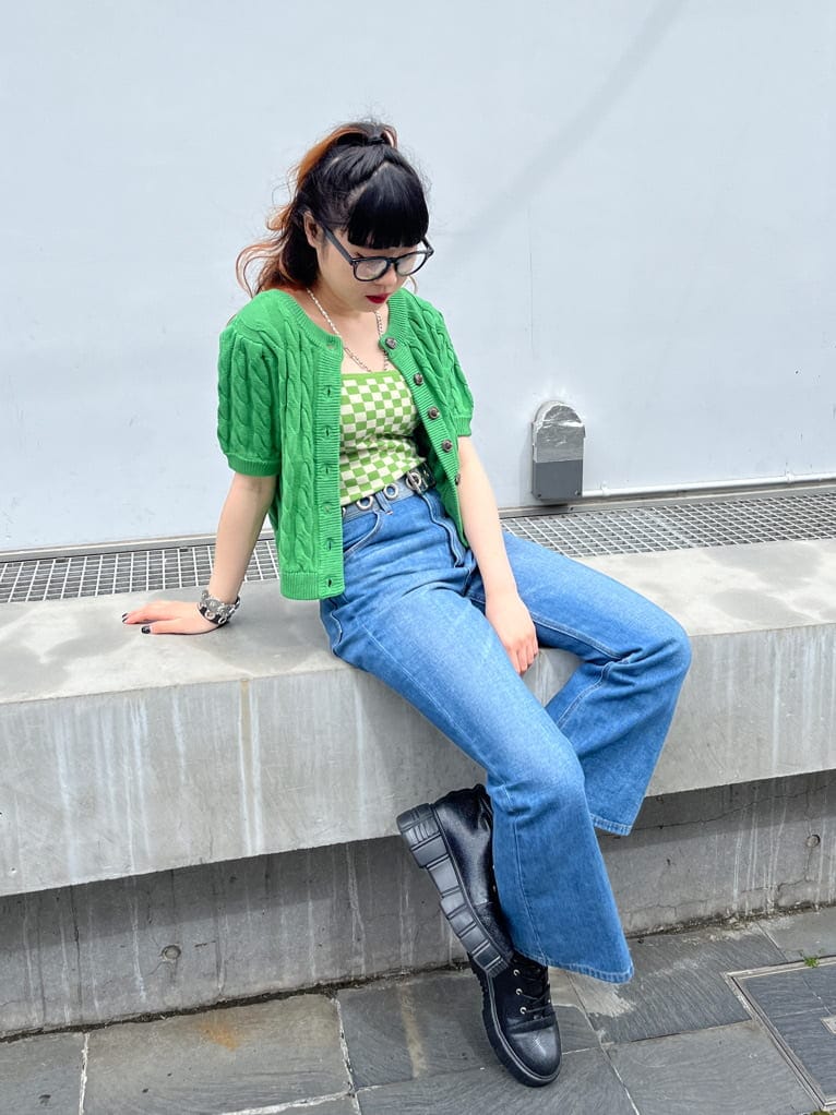 グリーン系のキャミソール、グリーン系のニット/セーター、ブラック系のサングラスを着用したレディースの春コーディネートの2枚目の写真