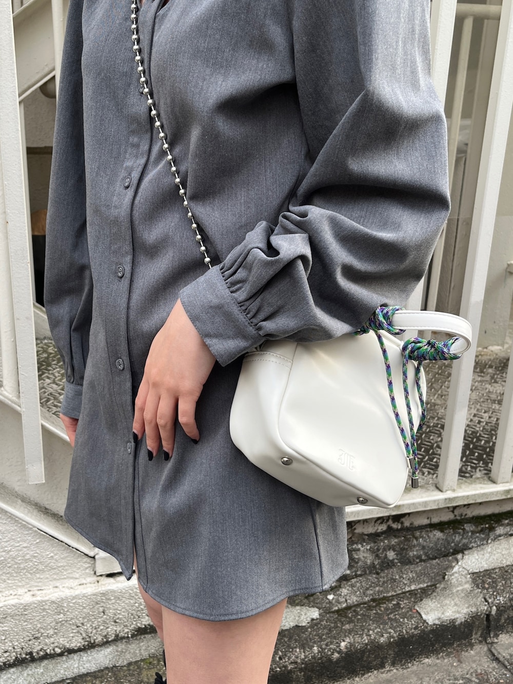 グレー系のワンピース、ブラック系のブーツ、ホワイト系のショルダーバッグを着用したレディースの冬コーディネートの8枚目の写真