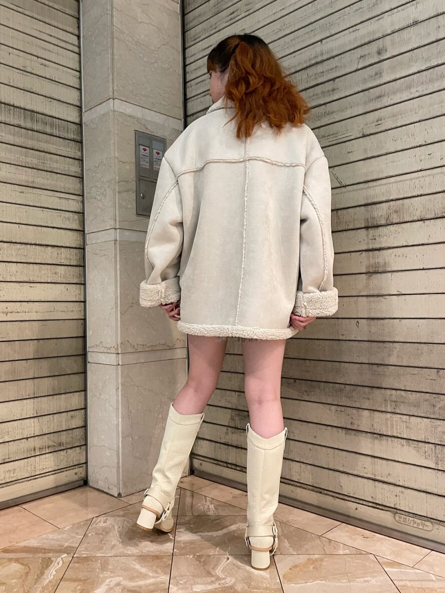 グリーン系のブーツ、ホワイト系のムートンコートを着用したレディースの夏コーディネートの2枚目の写真