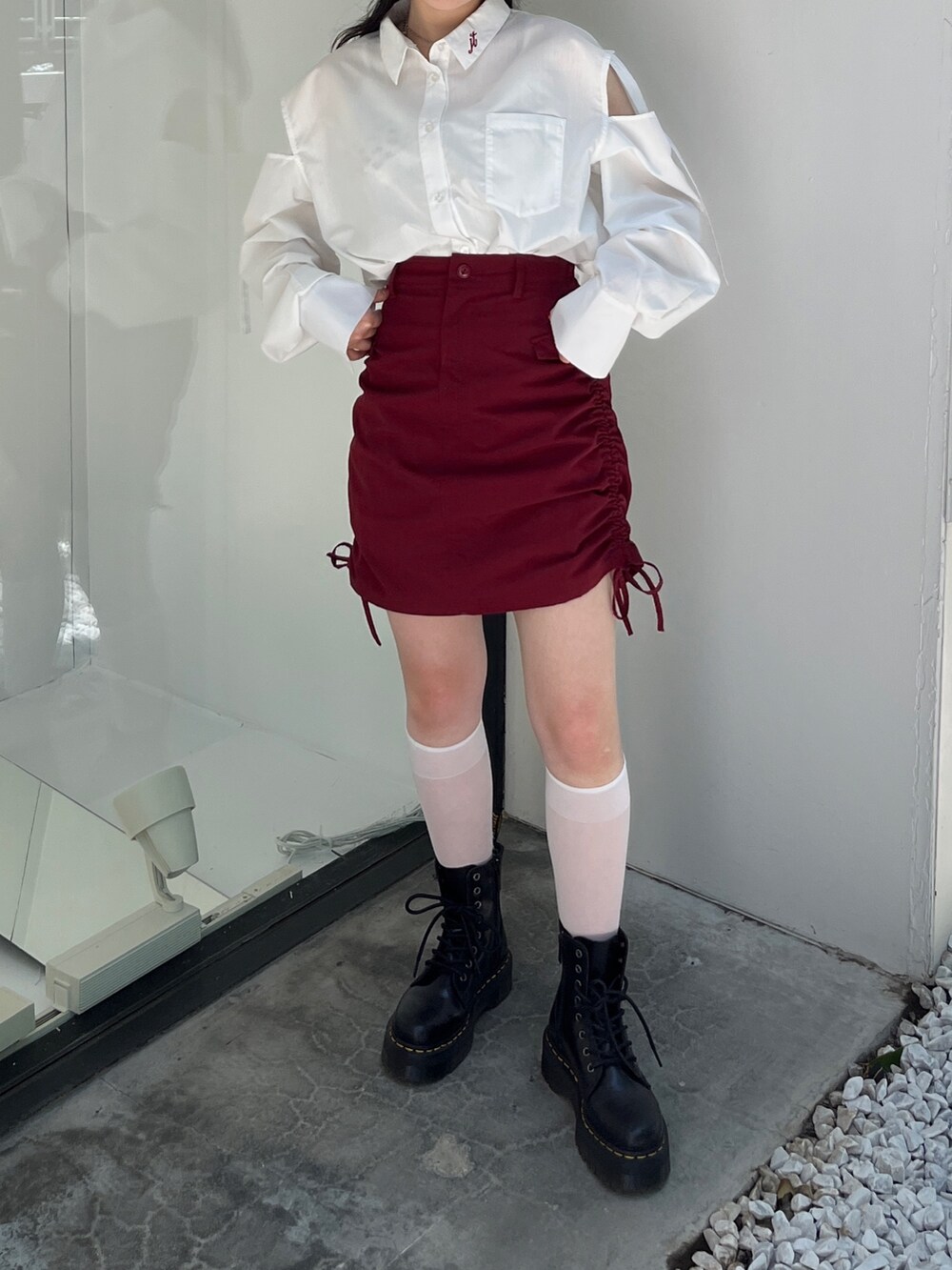 レッド系のスカート、ホワイト系のシャツ/ブラウス、ブラック系のキャップを着用したレディースの夏コーディネートの2枚目の写真