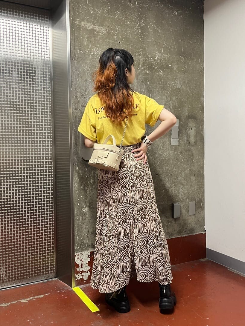 ブラック系のブーツ、ホワイト系のショルダーバッグ、その他のスカートを着用したレディースの春コーディネートの2枚目の写真