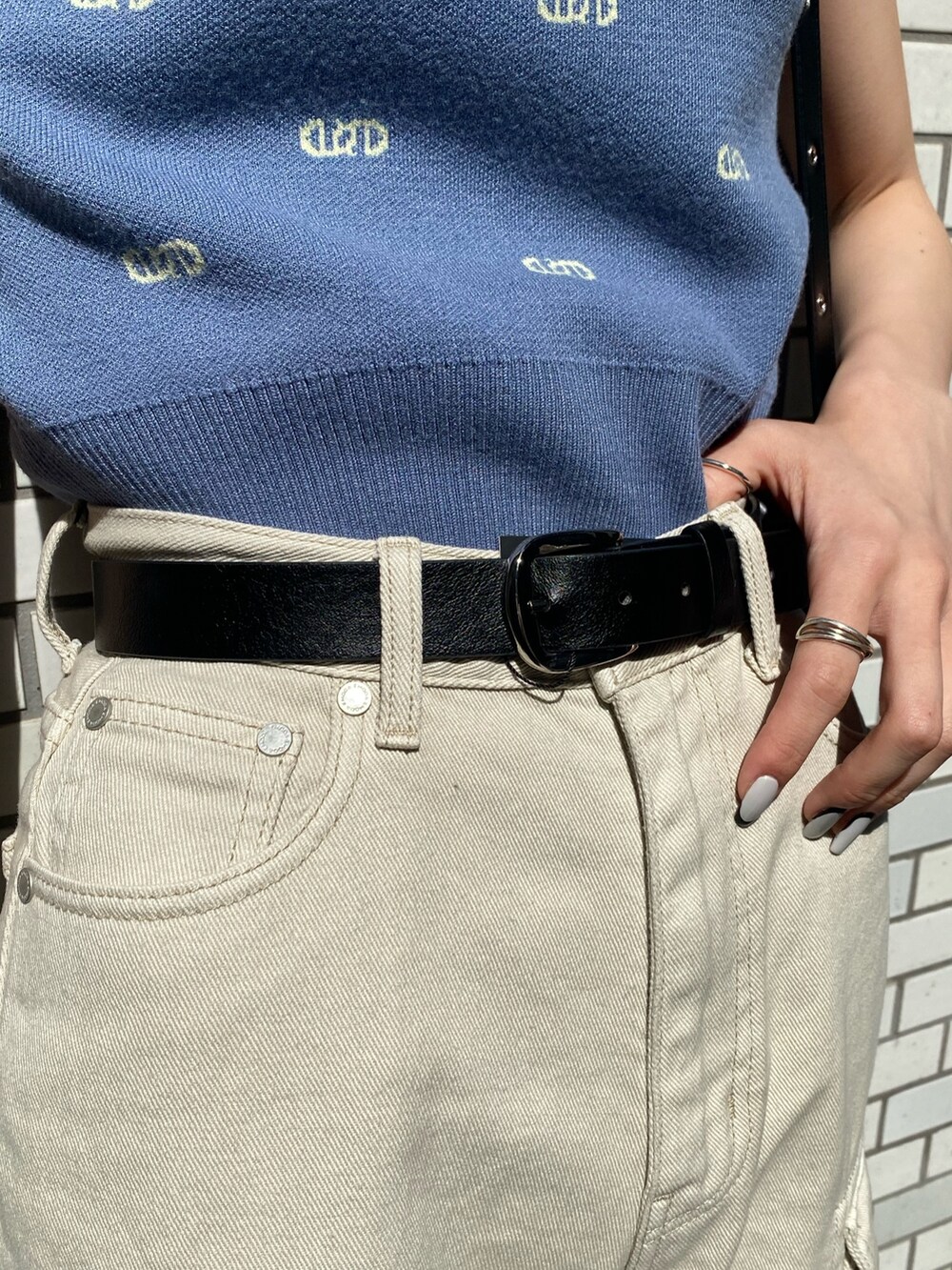 ブラック系のショルダーバッグ、ホワイト系のサンダル、ホワイト系のデニムパンツを着用したレディースの春コーディネートの9枚目の写真