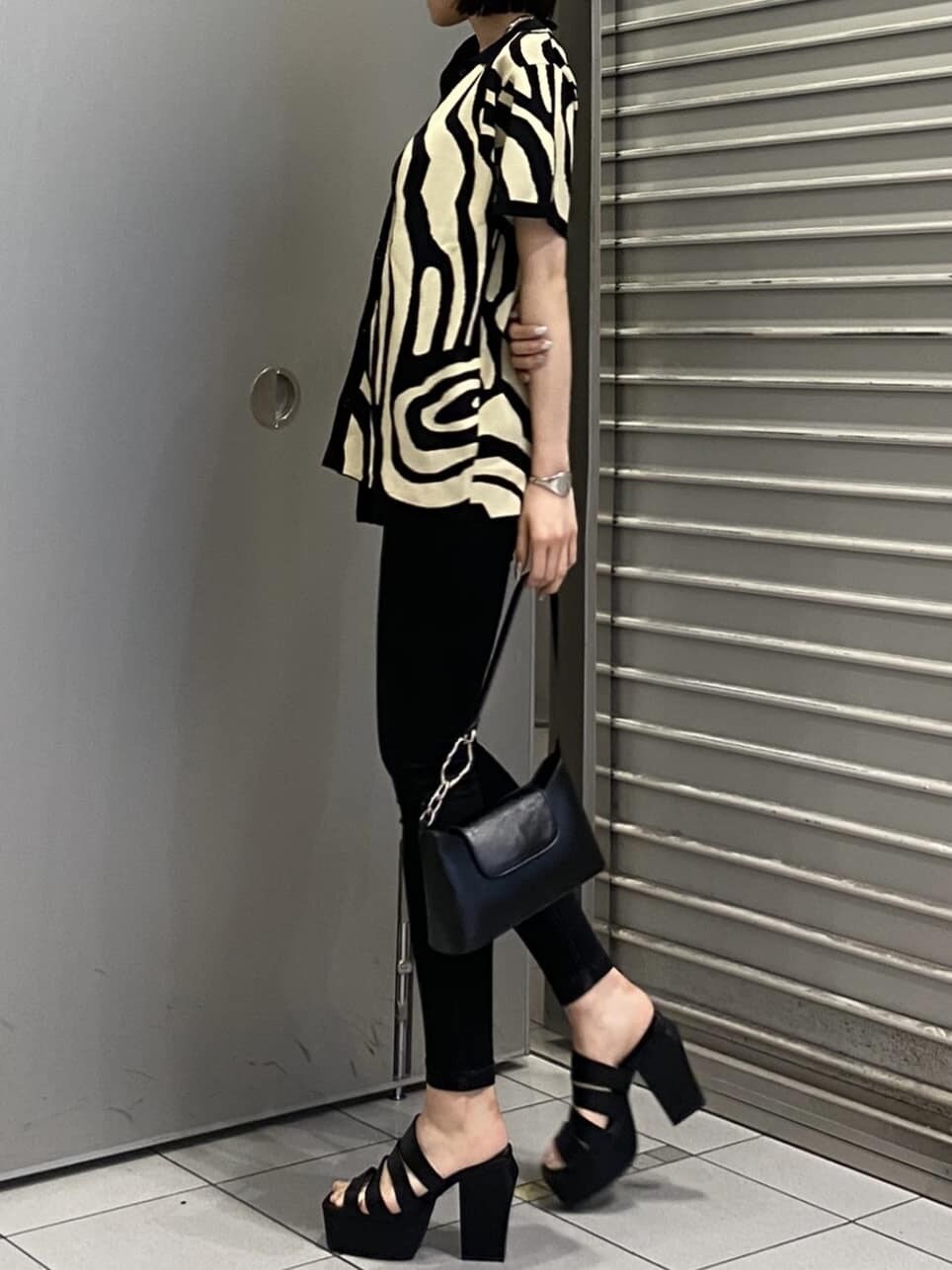 ブラック系のニット/セーター、ブラック系のサンダル、ブラック系のデニムパンツを着用したレディースの夏コーディネートの4枚目の写真