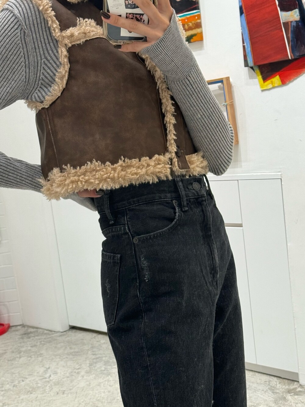 ブラック系のデニムパンツ、ブラウン系のベスト、グレー系のニット/セーターを着用したレディースの秋コーディネートの8枚目の写真