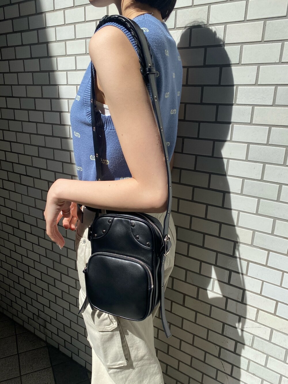 ブラック系のショルダーバッグ、ホワイト系のサンダル、ホワイト系のデニムパンツを着用したレディースの春コーディネートの10枚目の写真