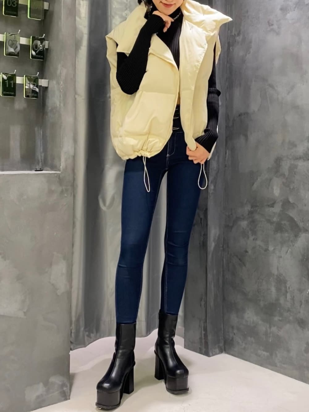ブルー系のデニムパンツ、ブラック系のブーツ、ホワイト系のダウンベストを着用したレディースの秋コーディネートの3枚目の写真