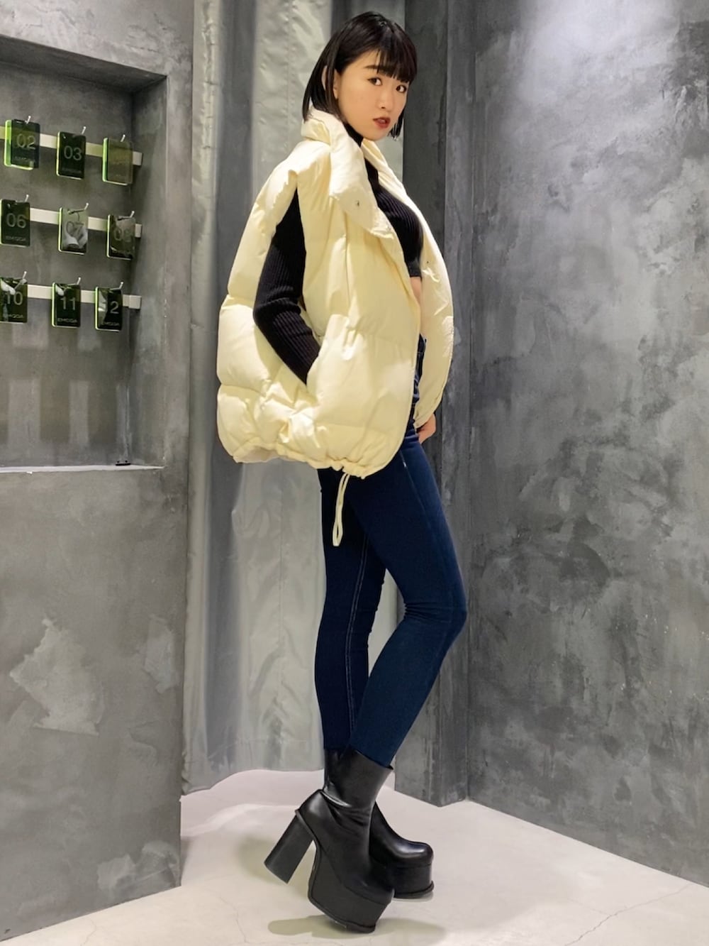 ブルー系のデニムパンツ、ブラック系のブーツ、ホワイト系のダウンベストを着用したレディースの秋コーディネートの2枚目の写真