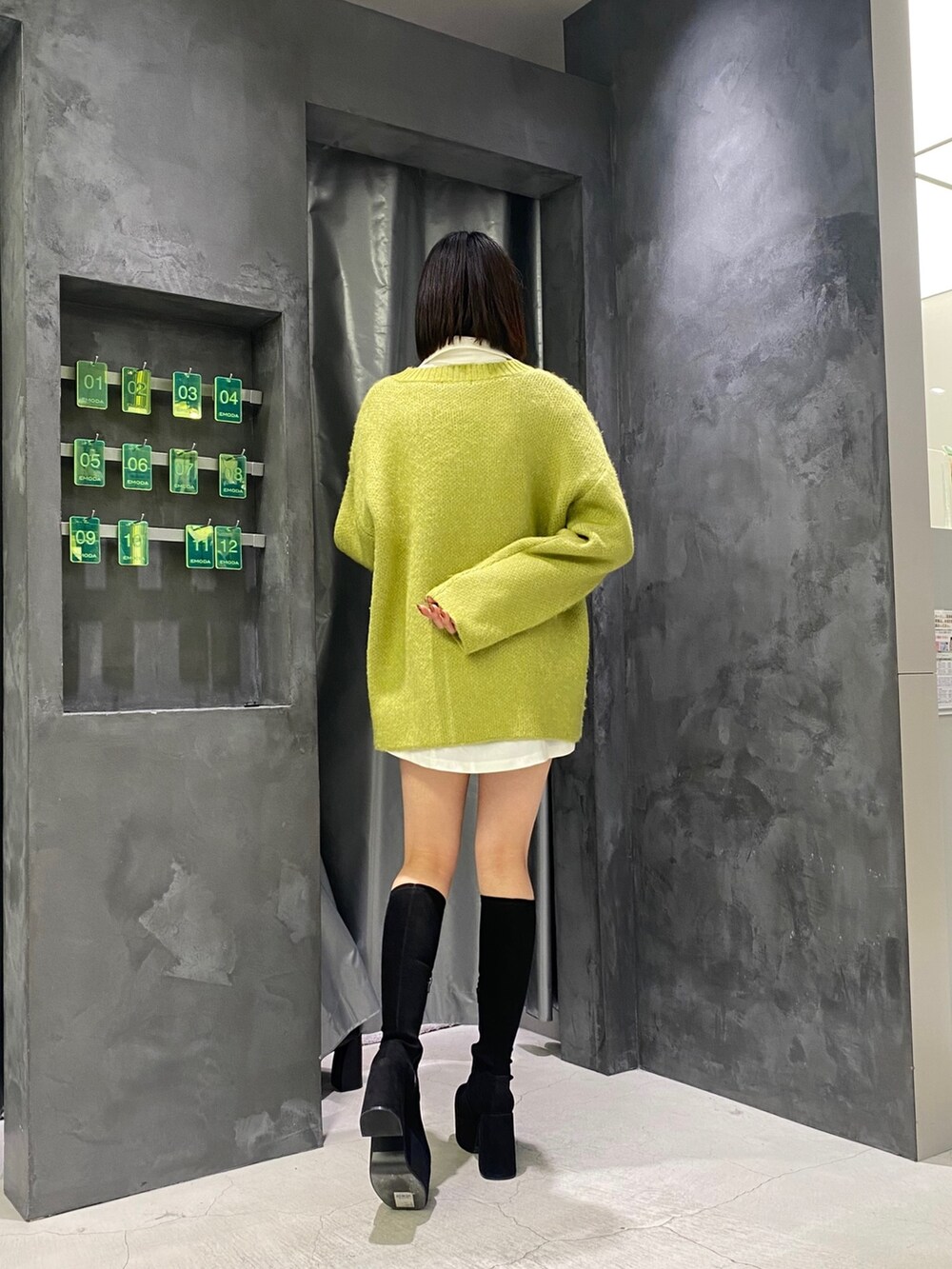 ブラック系のブーツ、イエロー系のニット/セーター、ホワイト系のワンピースを着用したレディースの冬コーディネートの5枚目の写真