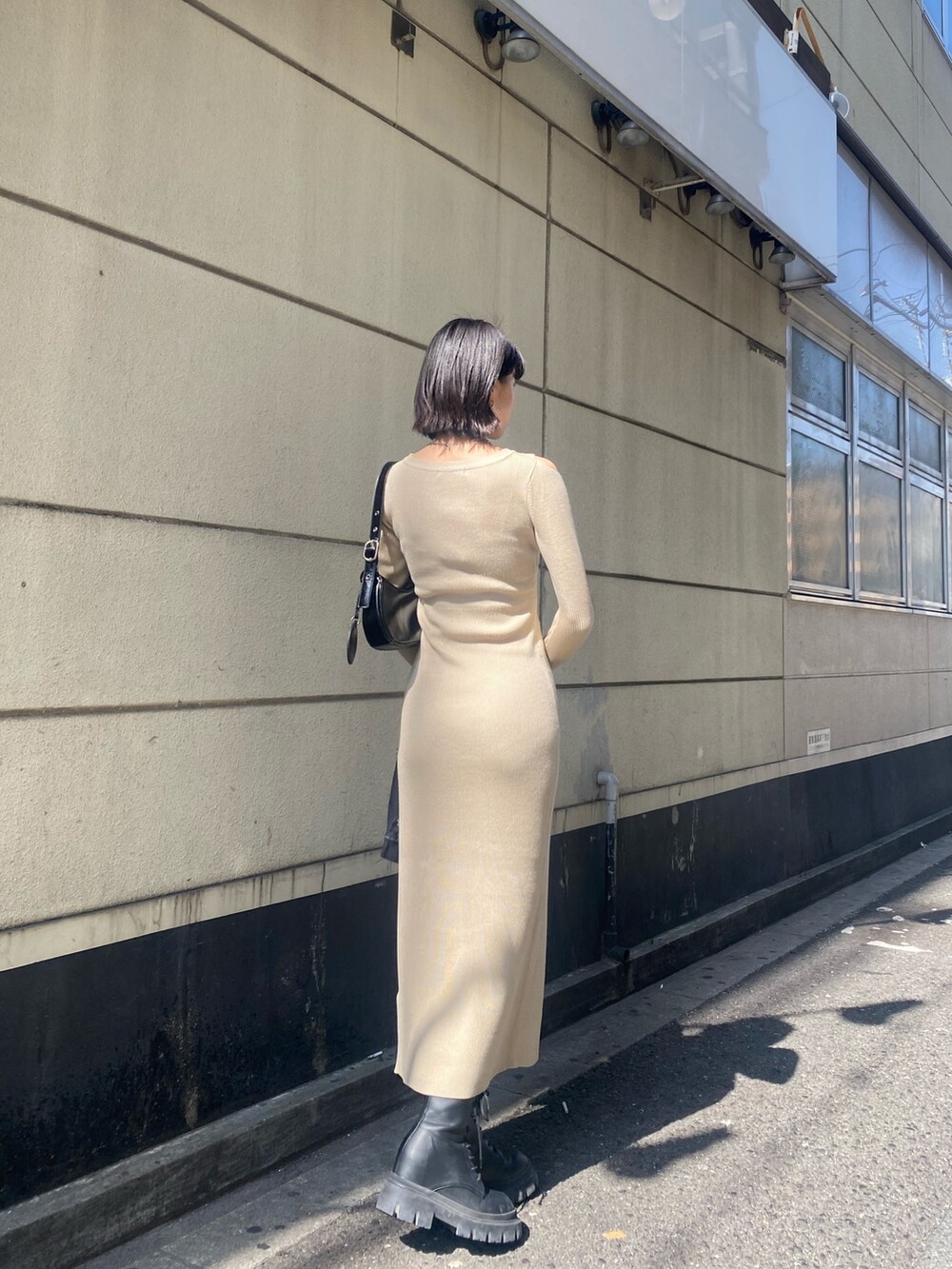 ブラック系のブーツ、ベージュ系のワンピース、ブラック系のデニムジャケットを着用したレディースの春コーディネートの3枚目の写真