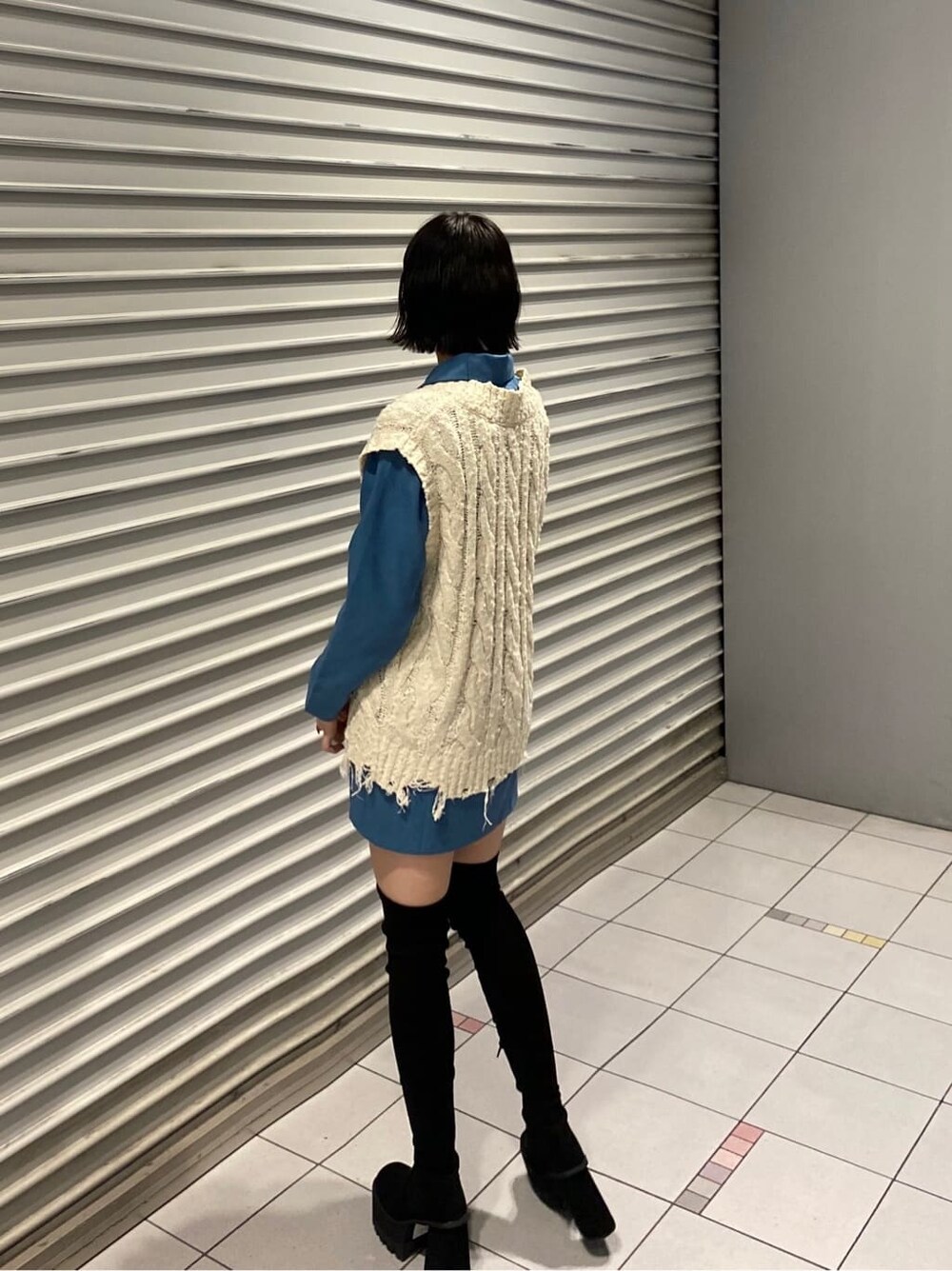 ホワイト系のベスト、ブルー系のワンピース、ブラック系のブーツを着用したレディースの夏コーディネートの4枚目の写真