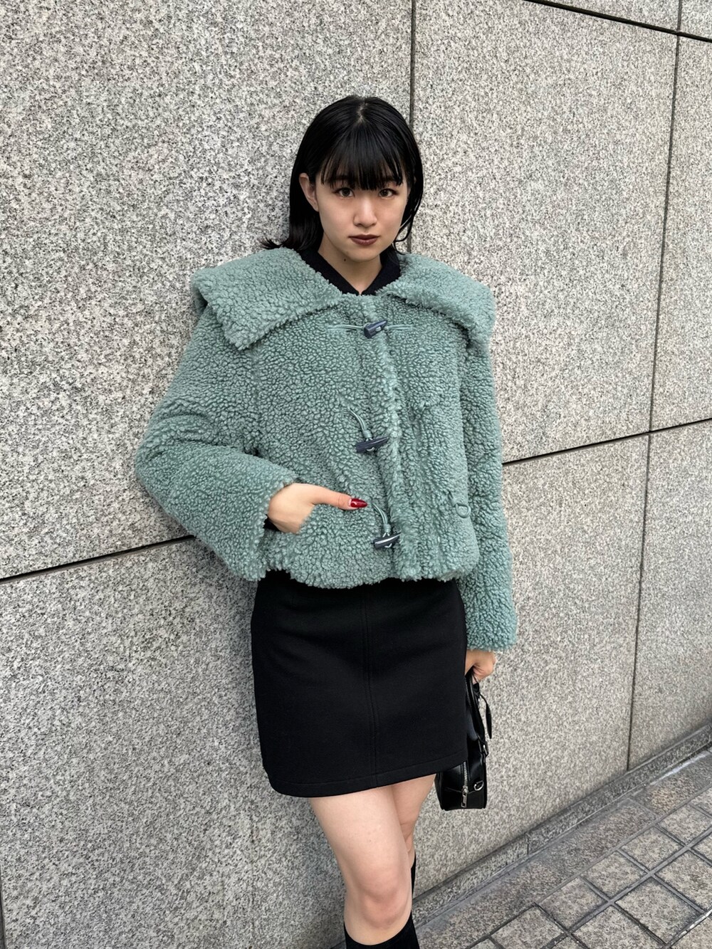 グリーン系のブルゾン、ブラック系のスカート、その他のブーツを着用したレディースの冬コーディネートの5枚目の写真