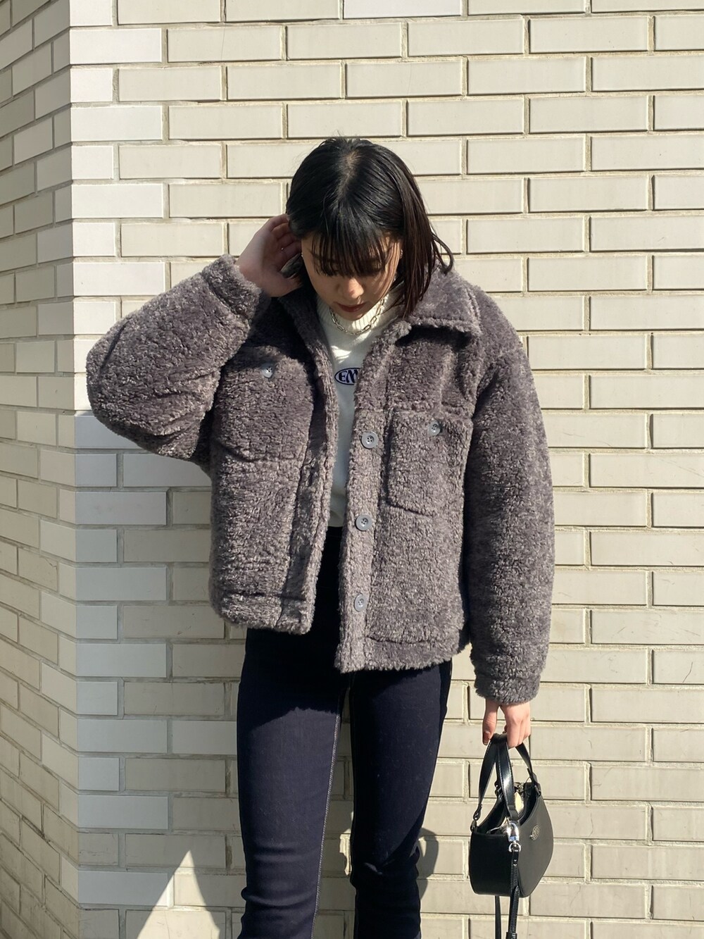 ブラック系のブーツ、ブラック系のハンドバッグ、グレー系のブルゾンを着用したレディースの冬コーディネートの6枚目の写真