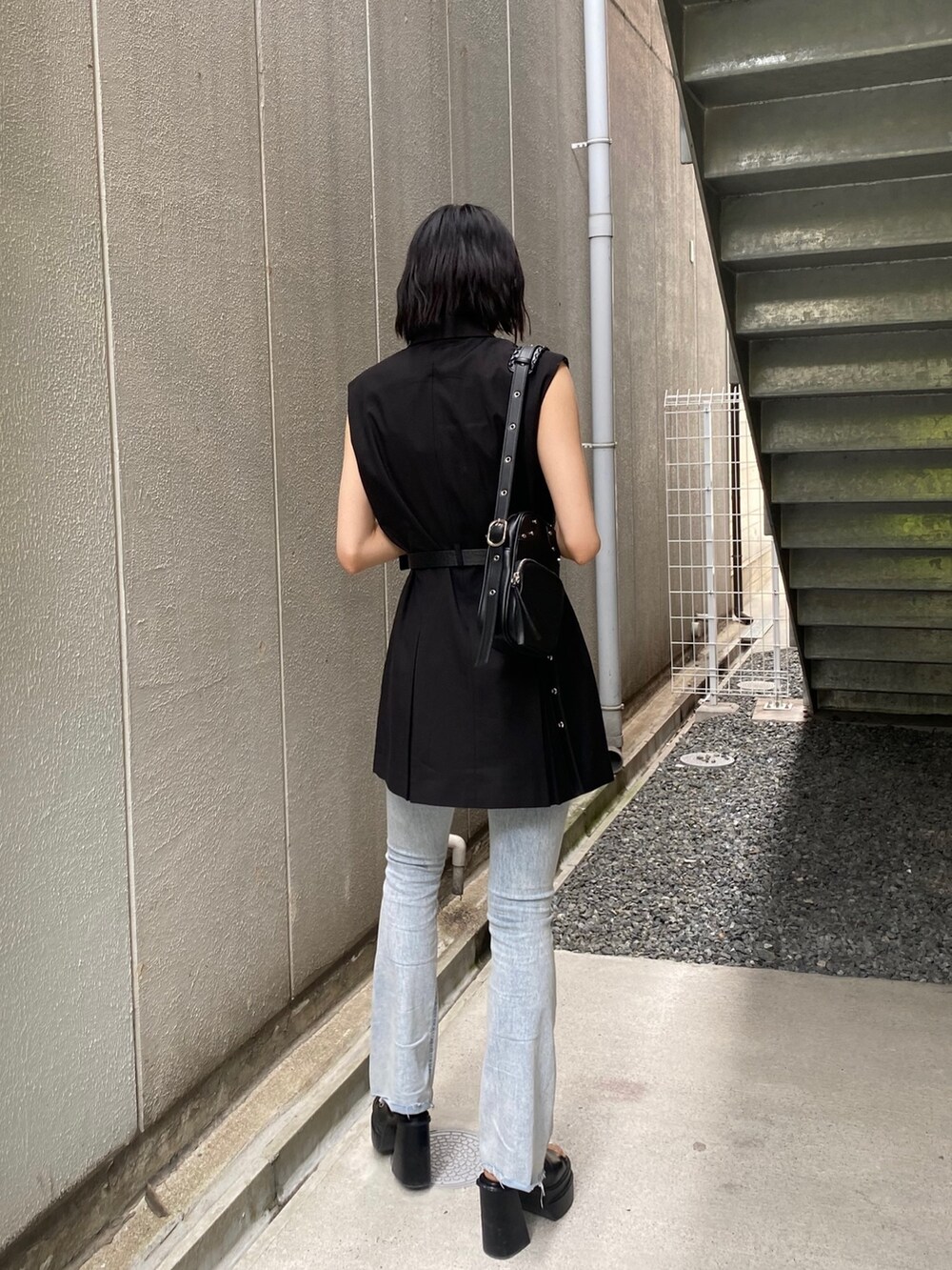 ブラック系のワンピース、ブラック系のサンダル、ブルー系のデニムパンツを着用したレディースの夏コーディネートの4枚目の写真