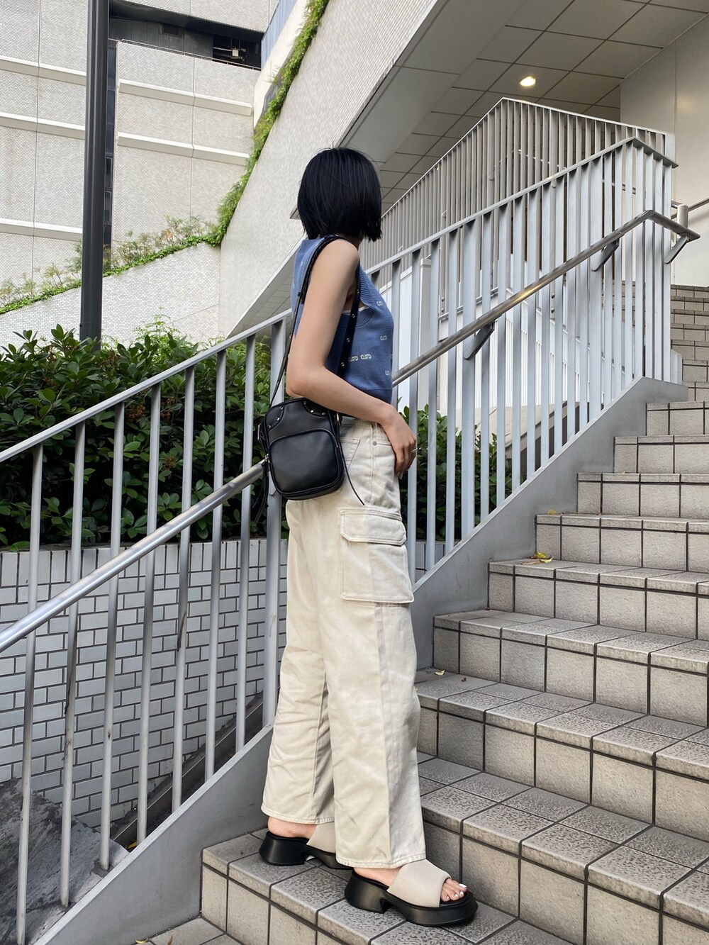 ブラック系のショルダーバッグ、ホワイト系のサンダル、ホワイト系のデニムパンツを着用したレディースの春コーディネートの5枚目の写真