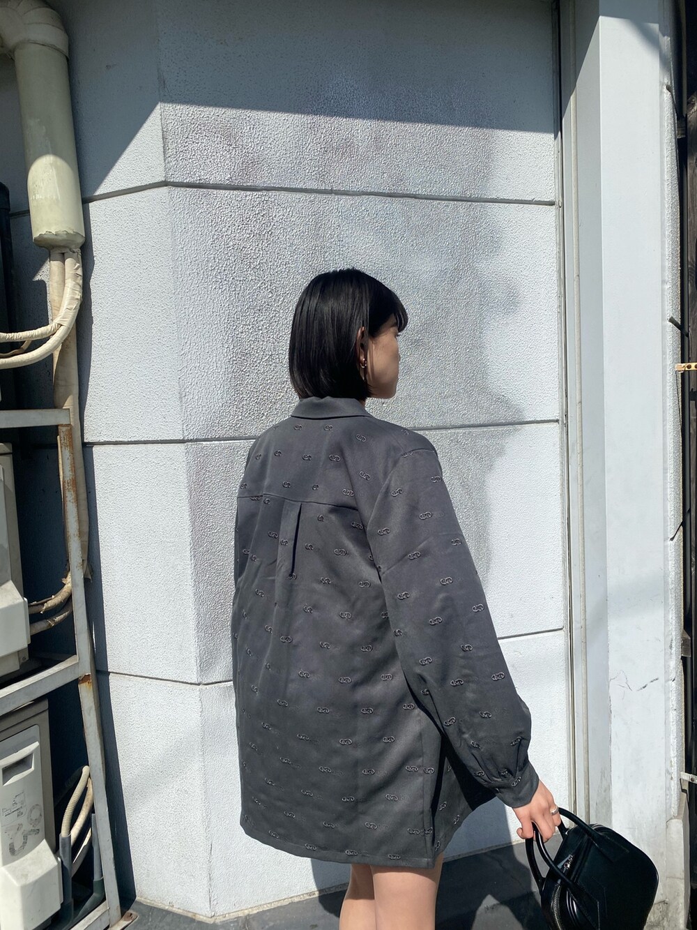グレー系のワンピース、ブラック系のハンドバッグ、ブラック系のブーツを着用したレディースの春コーディネートの9枚目の写真