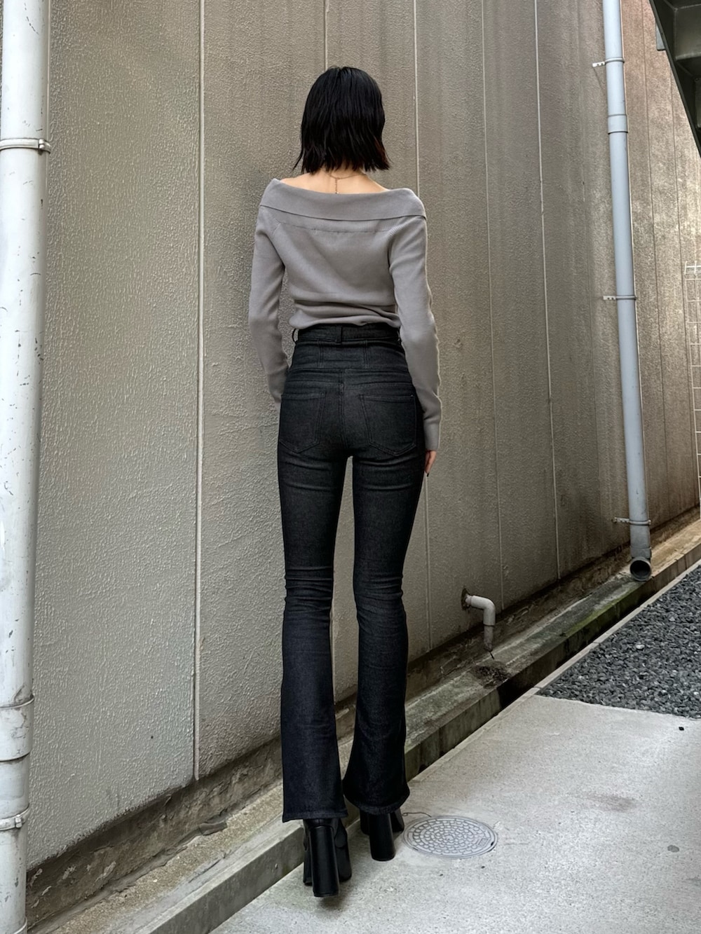 ブラック系のデニムパンツ、ブラック系のブーツ、グレー系のニット/セーターを着用したレディースの秋コーディネートの5枚目の写真