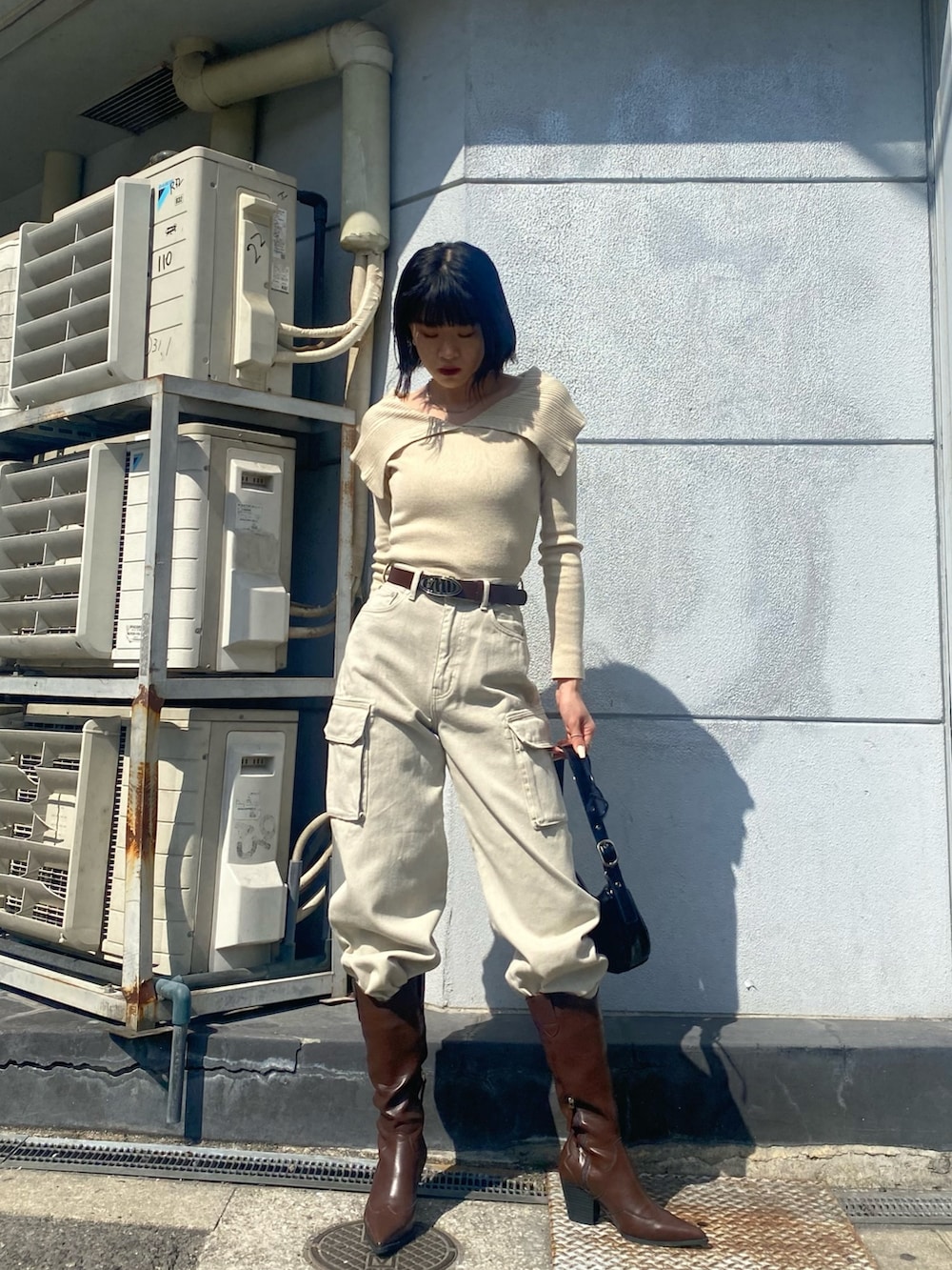 ブラウン系のブーツ、ホワイト系のデニムパンツ、ブラック系のハンドバッグを着用したレディースの春コーディネートの2枚目の写真