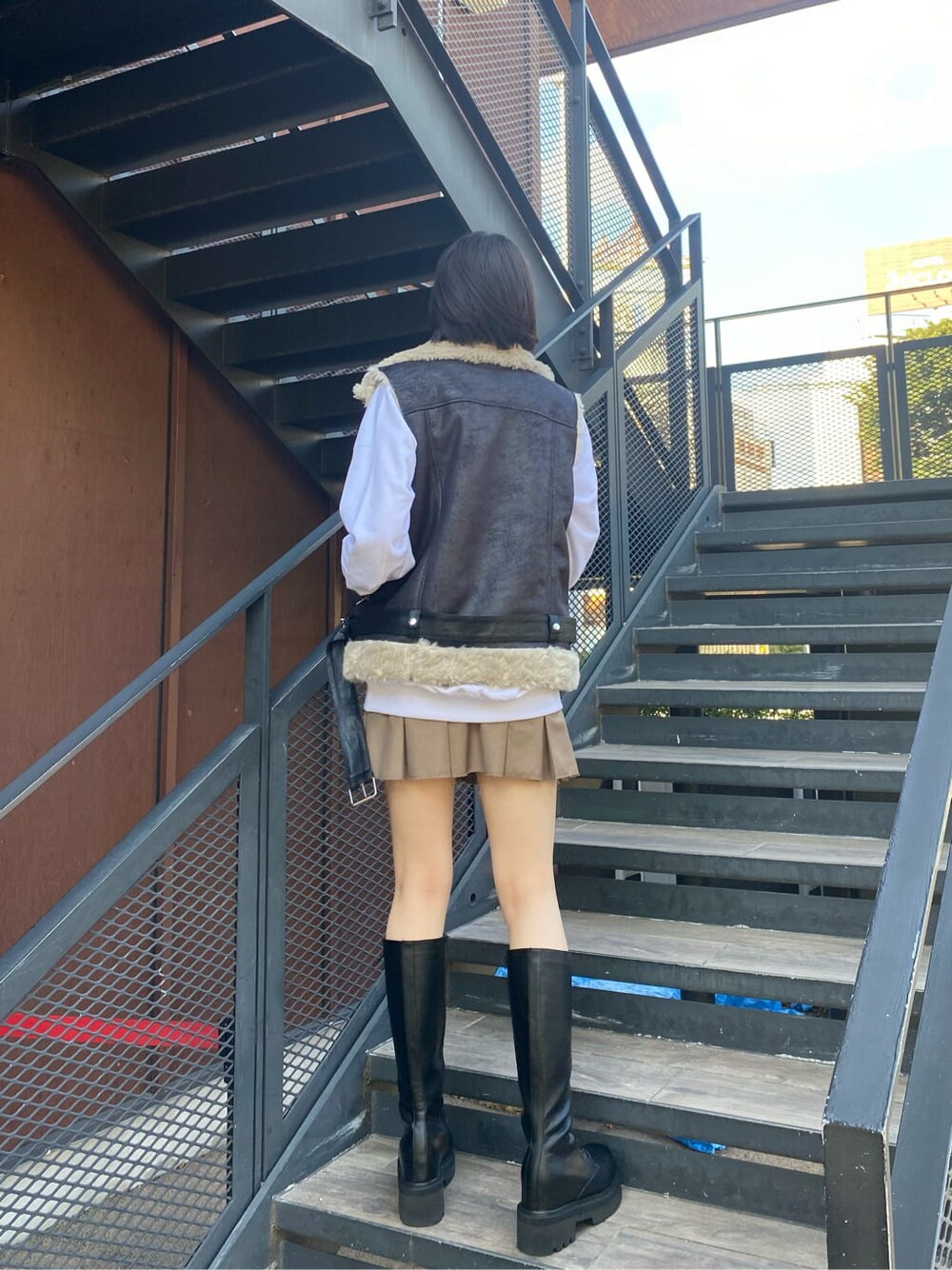 ブラック系のブーツ、ベージュ系のスカート、ブラック系のベストを着用したレディースの秋コーディネートの3枚目の写真