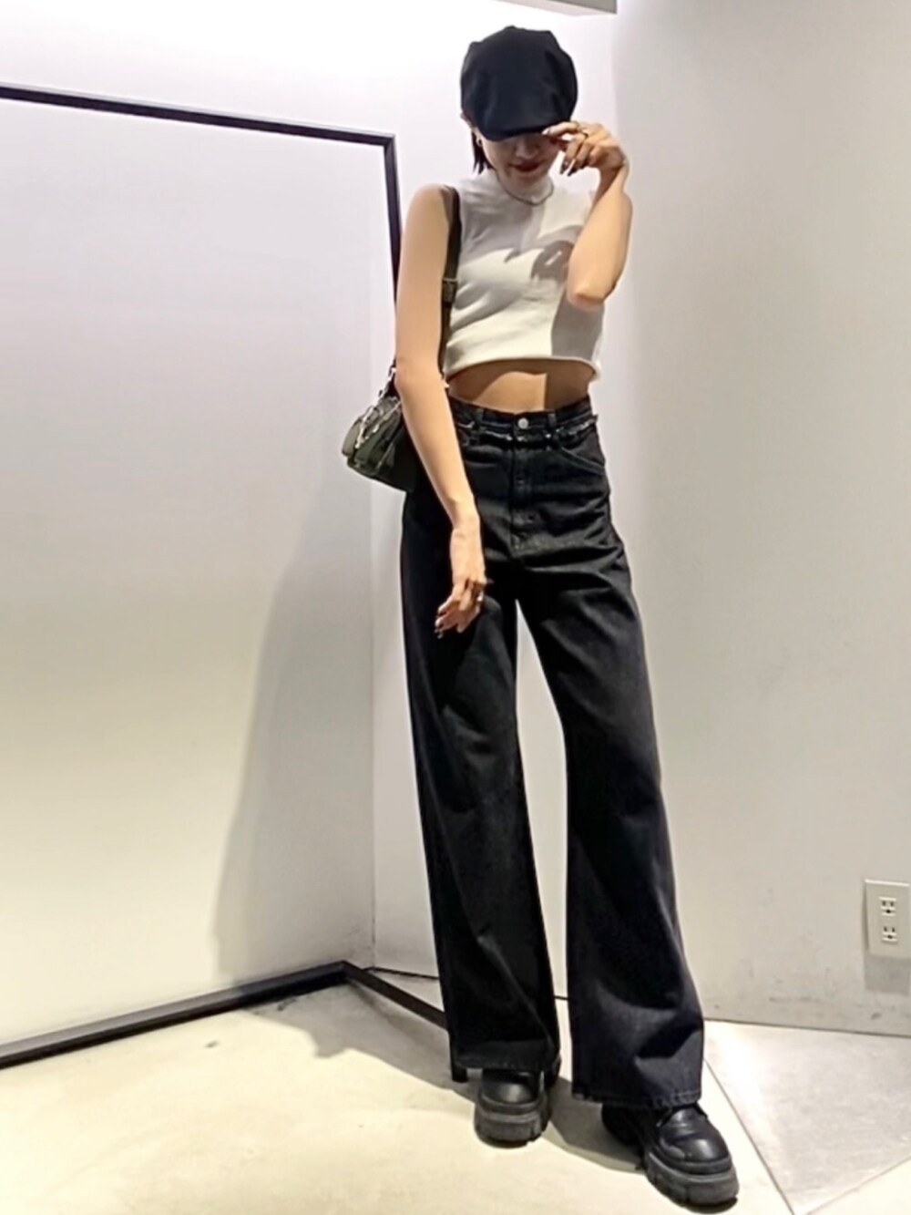 ブラック系のデニムパンツ、ブラック系のブーツ、グリーン系のハンドバッグを着用したレディースの夏コーディネートの2枚目の写真