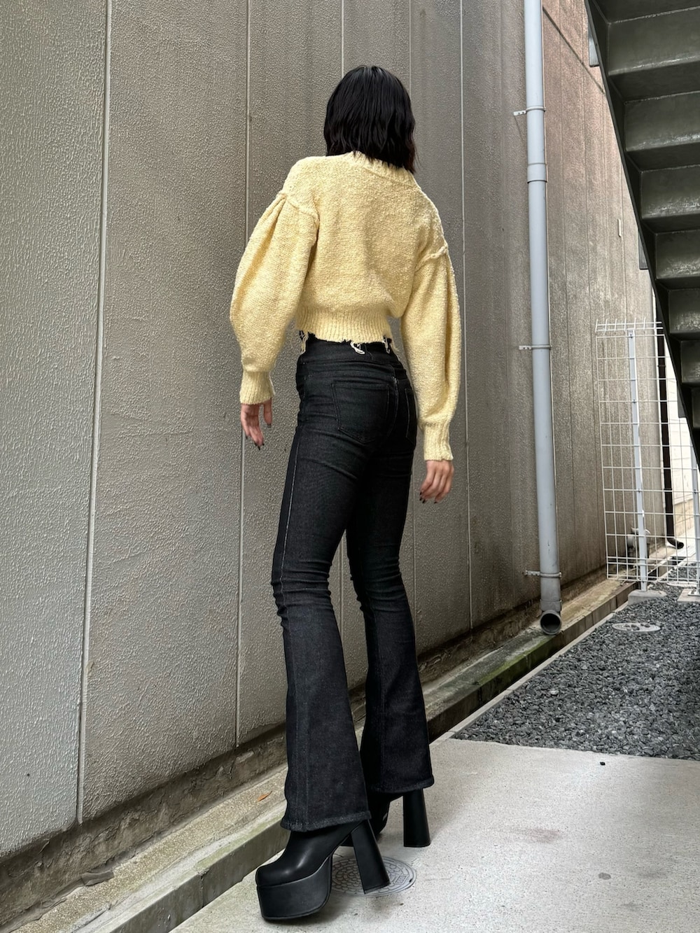 ブラック系のブーツ、ブラック系のデニムパンツ、イエロー系のカーディガン/ボレロを着用したレディースの秋コーディネートの3枚目の写真