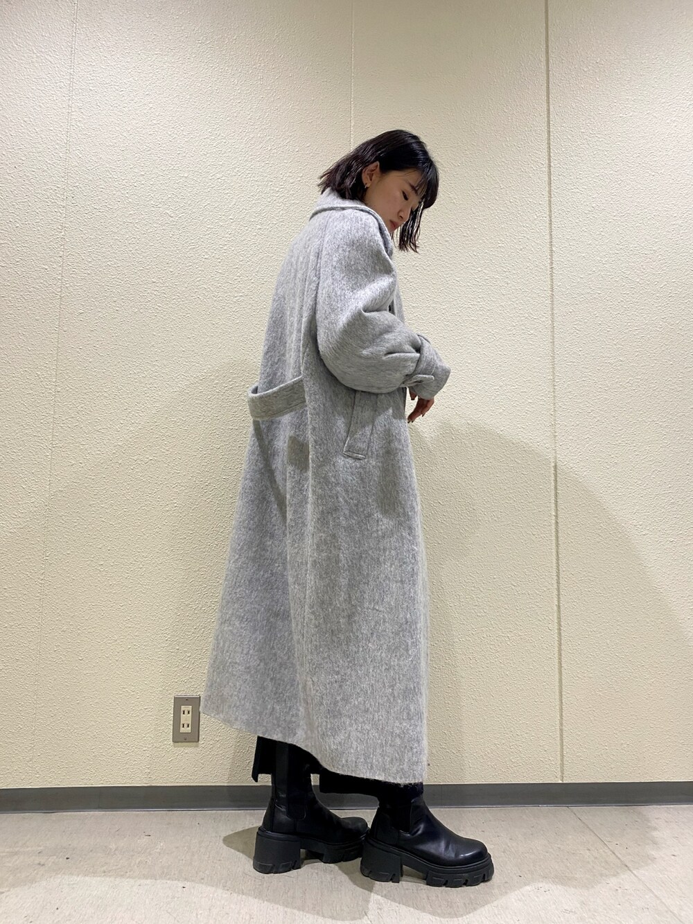 ブラック系のブーツ、グレー系のチェスターコート、ブラック系のスカートを着用したレディースの冬コーディネートの4枚目の写真