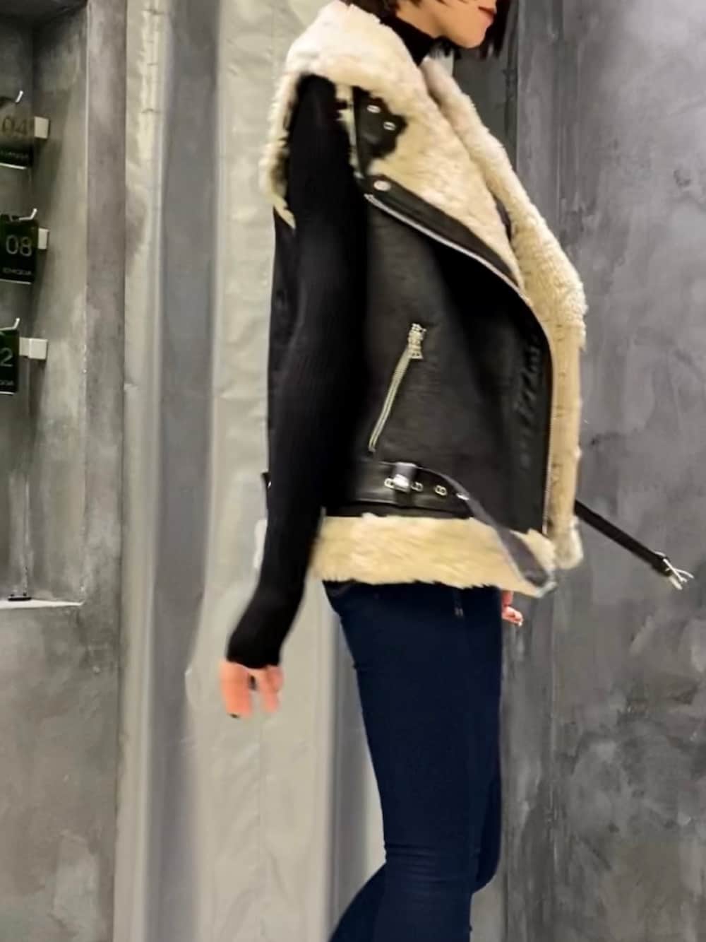 ブルー系のデニムパンツ、ブラック系のブーツ、ブラック系のベストを着用したレディースの秋コーディネートの4枚目の写真