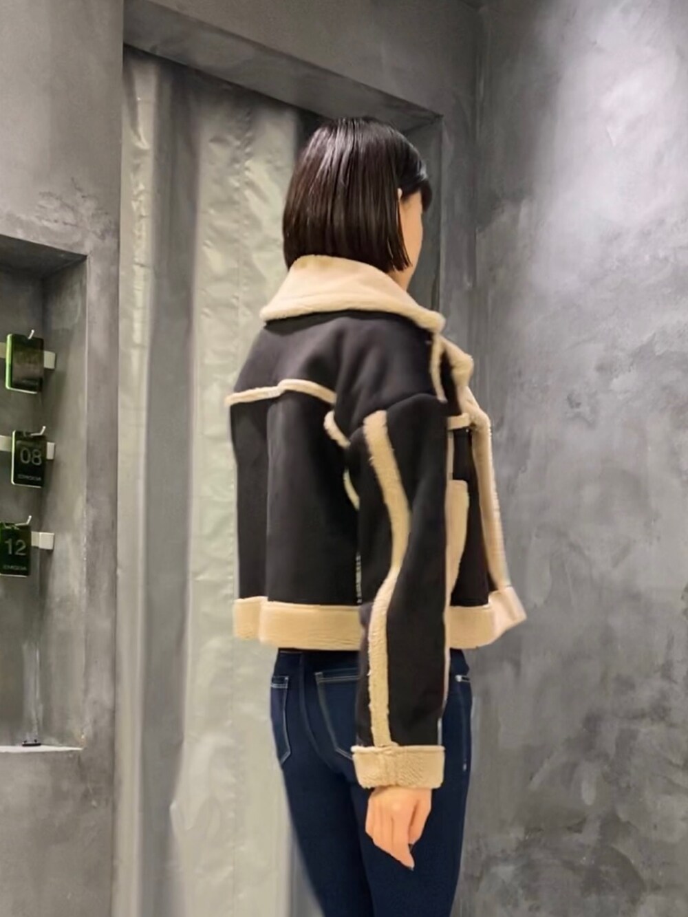 ブルー系のデニムパンツ、ブラック系のブーツ、ブラック系のムートンコートを着用したレディースの秋コーディネートの4枚目の写真