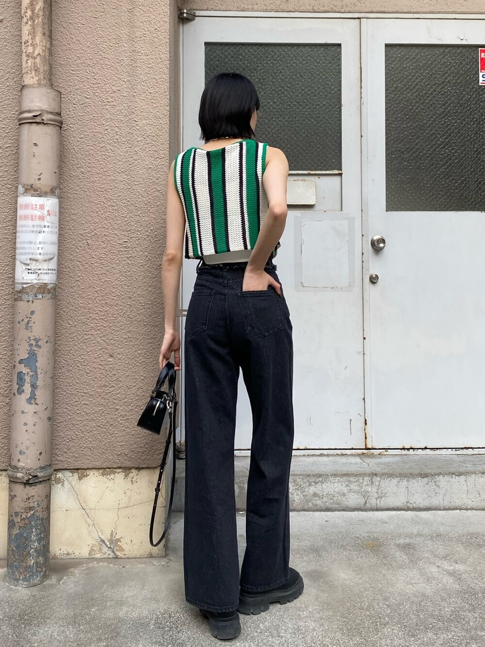 ブラック系のデニムパンツ、ブラック系のブーツ、ブラック系のハンドバッグを着用したレディースの春コーディネートの9枚目の写真