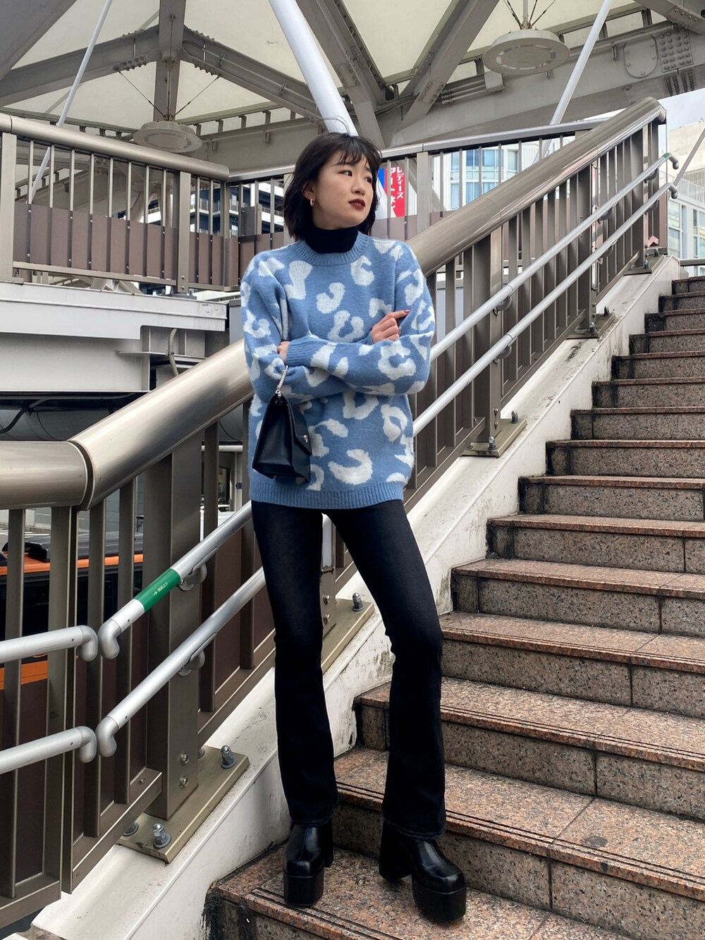 ブルー系のニット/セーター、ブラック系のハンドバッグ、ブラック系のブーツを着用したレディースの冬コーディネートの3枚目の写真