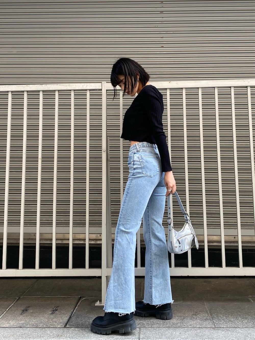 ブルー系のデニムパンツ、ブラック系のTシャツ/カットソー、シルバー系のハンドバッグを着用したレディースの春コーディネートの4枚目の写真
