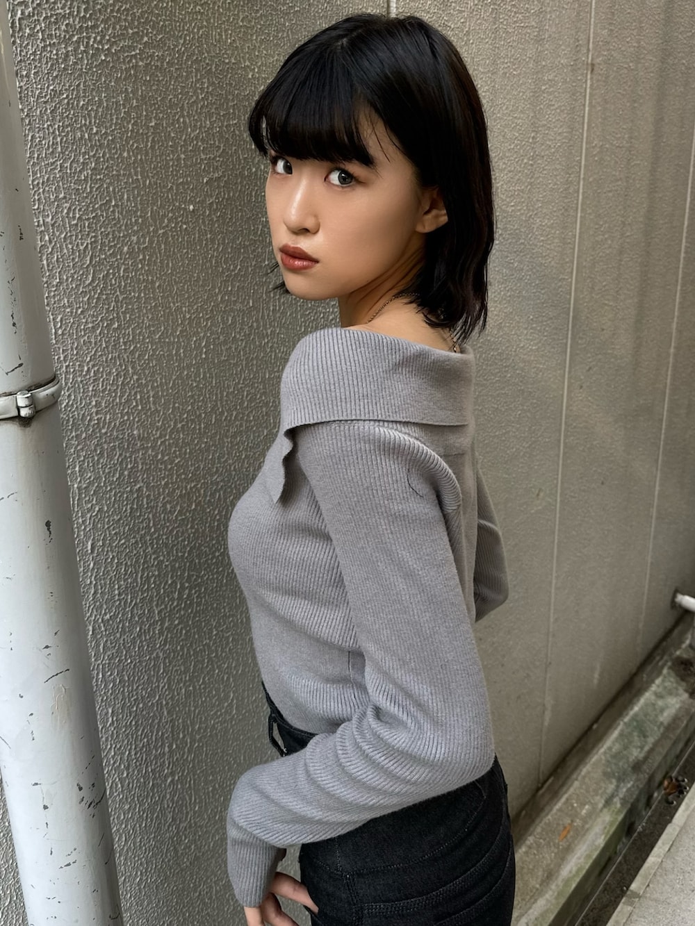 ブラック系のデニムパンツ、ブラック系のブーツ、グレー系のニット/セーターを着用したレディースの秋コーディネートの8枚目の写真